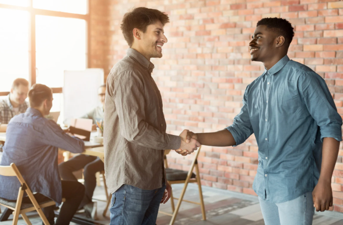 Two colleagues shaking hands in a modern office, symbolizing successful partnership and collaboration